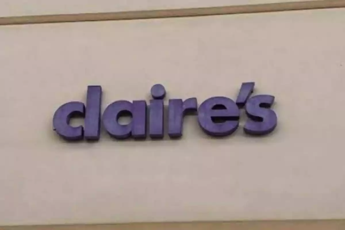 Letrero morado de la tienda Claire's sobre una pared beige Letrero morado de la tienda Claire's sobre una pared beige