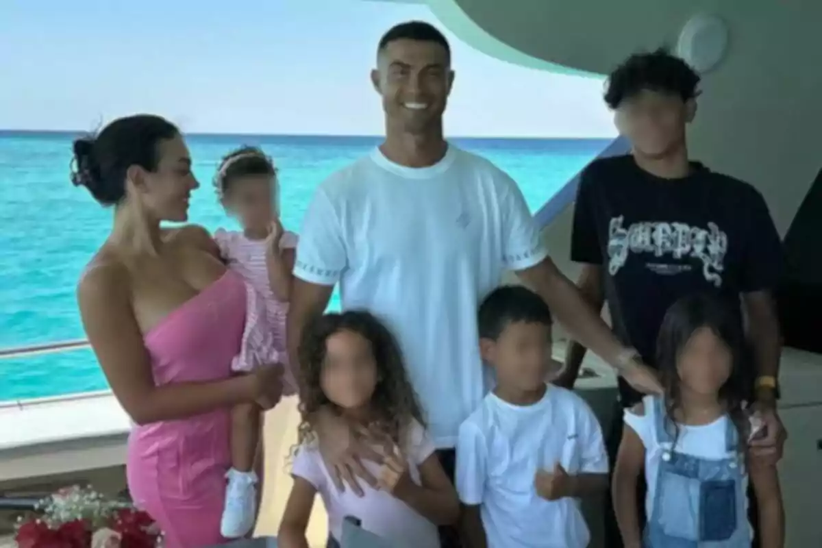 Família posant somrient en un iot amb el mar blau de fons Família posant somrient en un iot amb el mar blau de fons