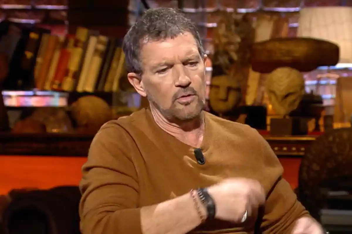 Antonio Banderas, vestido con suéter marrón, sentado en un ambiente con libros y objetos decorativos al fondo. Captura de 'Cuarto Milenio' Antonio Banderas, vestido con suéter marrón, sentado en un ambiente con libros y objetos decorativos al fondo. Captura de 'Cuarto Milenio'
