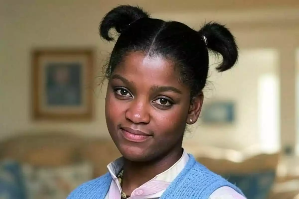 Danielle Spencer con peinado de dos coletas y chaleco azul mirando a la cámara con una expresión amigable en un ambiente interior desenfocado. Danielle Spencer con peinado de dos coletas y chaleco azul mirando a la cámara con una expresión amigable en un ambiente interior desenfocado.