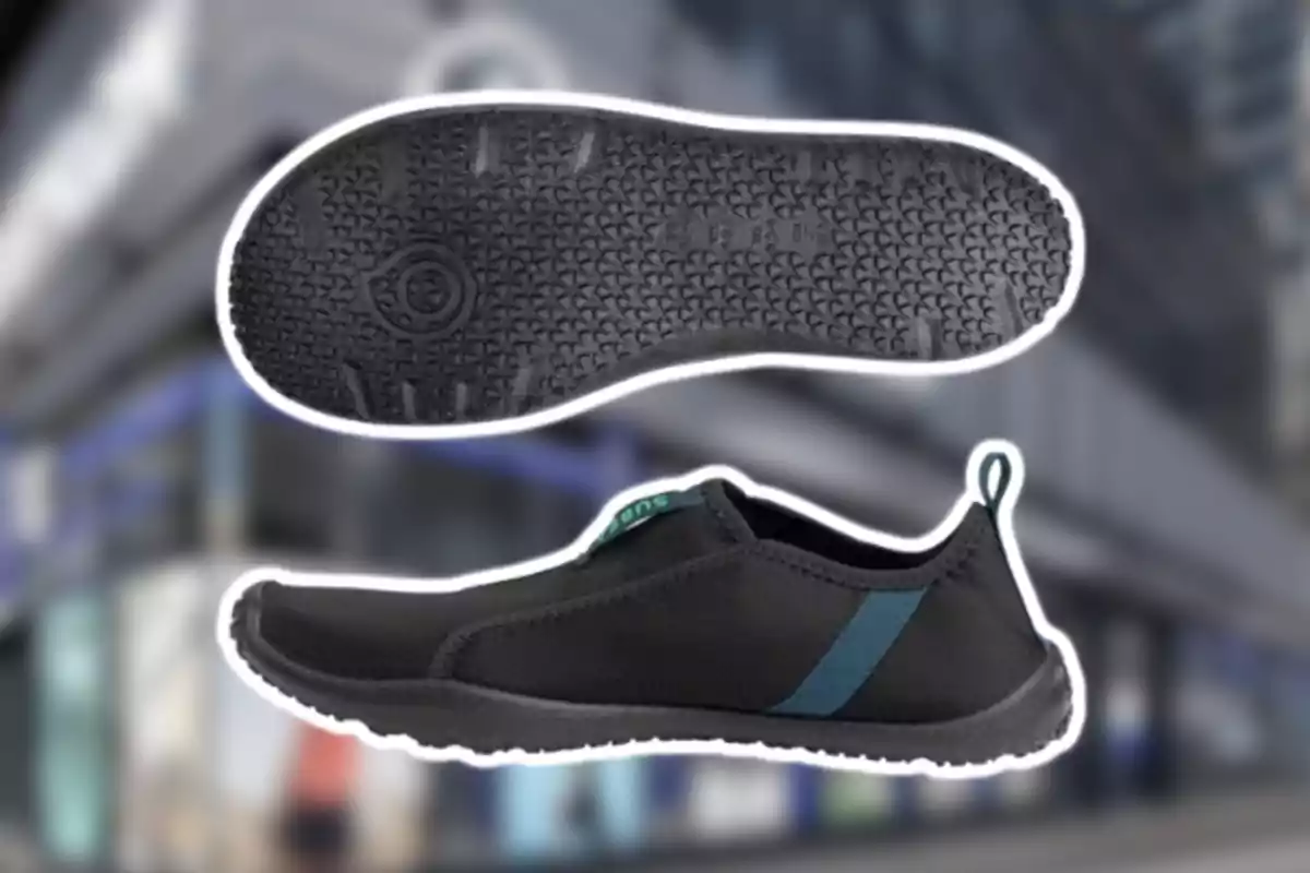 Sabata esportiva negra amb sola de goma texturitzada i detall blau al lateral sobre un fons urbà desenfocat Sabata esportiva negra amb sola de goma texturitzada i detall blau al lateral sobre un fons urbà desenfocat