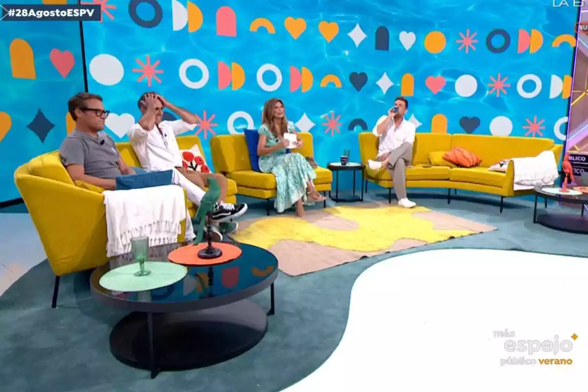 Quatre persones assegudes en sofàs grocs en un plató de televisió colorit amb fons blau i figures geomètriques. Captura d’'Espejo Público' Quatre persones assegudes en sofàs grocs en un plató de televisió colorit amb fons blau i figures geomètriques. Captura d’'Espejo Público'