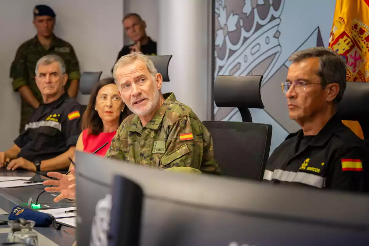 Reunió d’alts comandaments militars i una funcionària en una sala de conferències amb banderes i símbols oficials d’Espanya al fons Reunió d’alts comandaments militars i una funcionària en una sala de conferències amb banderes i símbols oficials d’Espanya al fons
