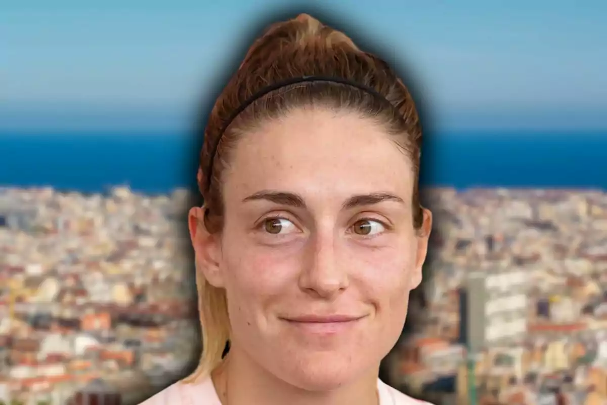 Mujer joven con diadema negra y expresión sonriente frente a un fondo desenfocado de ciudad y mar
