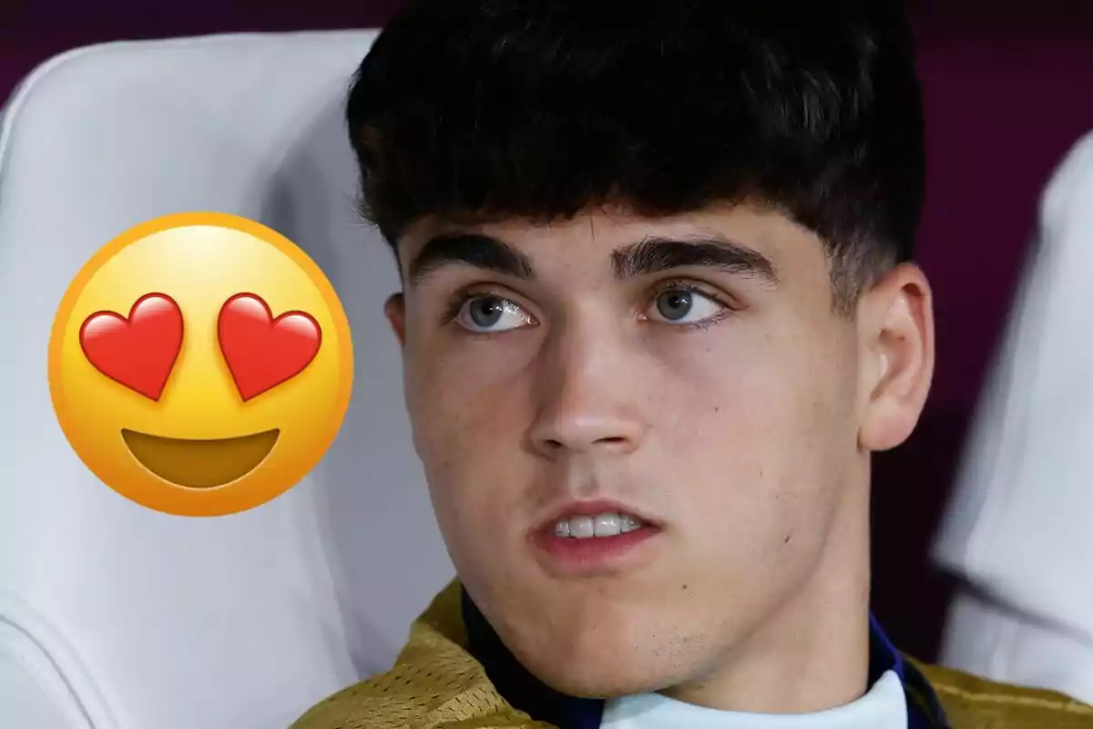 Joven de cabello oscuro sentado con una chaqueta dorada y un emoji de cara sonriente con ojos de corazón a la izquierda