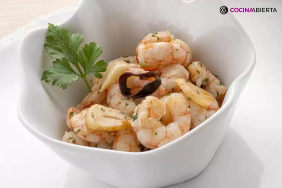 Gambes a l’all servides en un plat blanc decorades amb una branqueta de julivert Gambes a l’all servides en un plat blanc decorades amb una branqueta de julivert
