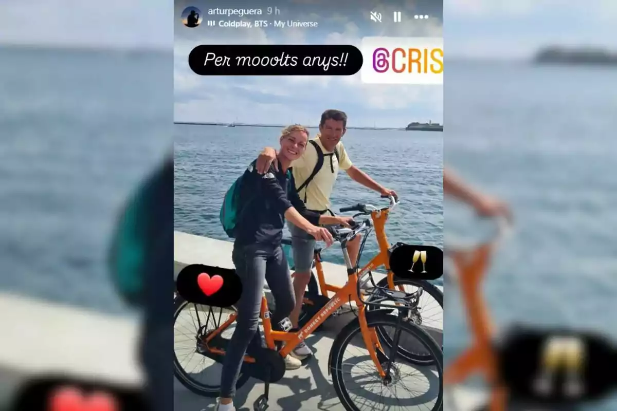 Dos personas sonrientes posan junto al mar montando bicicletas naranjas, una de ellas lleva una mochila verde y hay emojis de corazón y copas de brindis en la imagen Dos personas sonrientes posan junto al mar montando bicicletas naranjas, una de ellas lleva una mochila verde y hay emojis de corazón y copas de brindis en la imagen