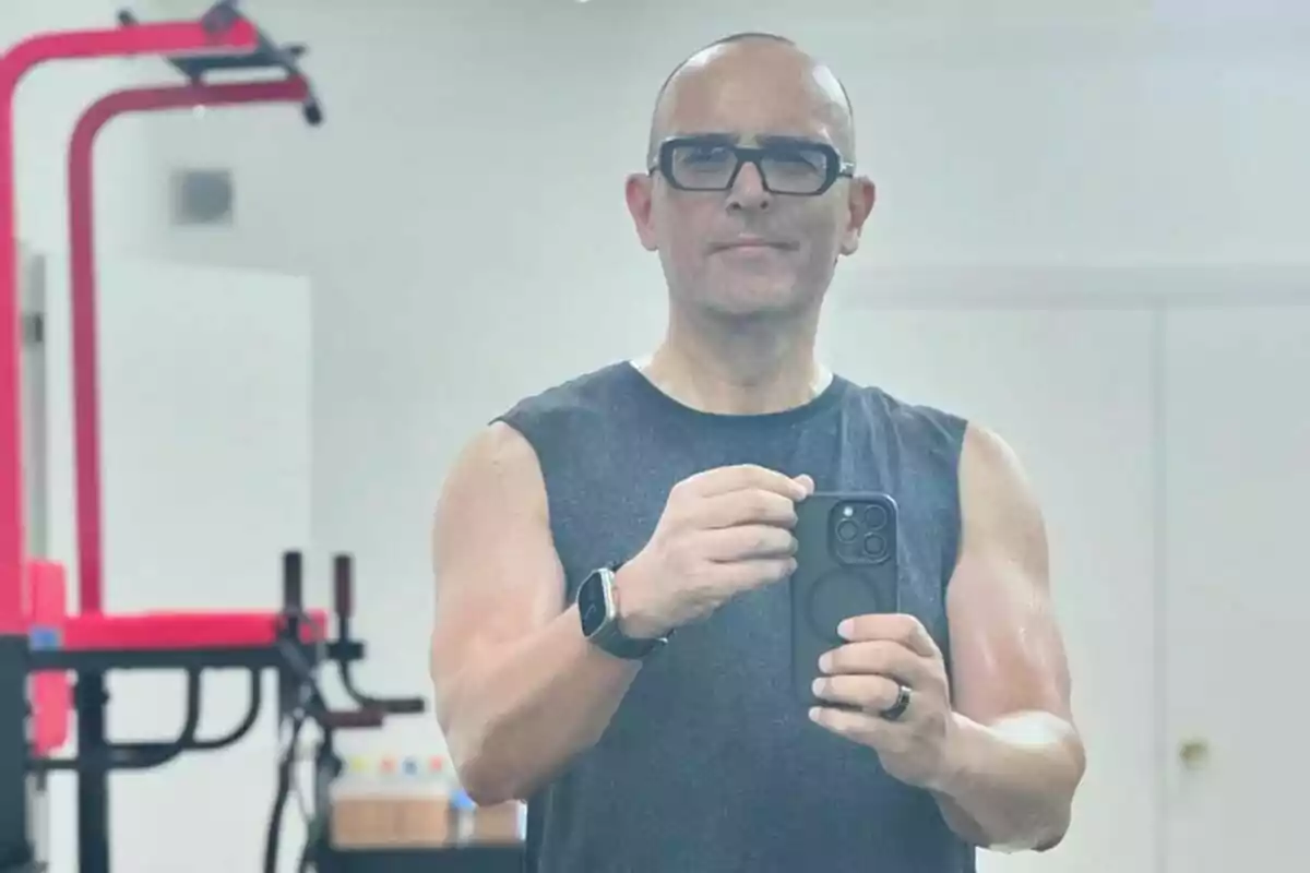 Hombre con gafas tomándose una selfie en el gimnasio usando camiseta sin mangas y reloj inteligente Hombre con gafas tomándose una selfie en el gimnasio usando camiseta sin mangas y reloj inteligente
