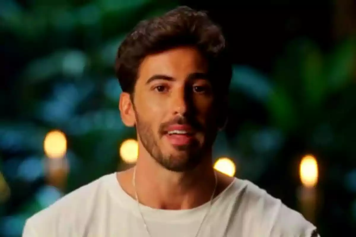 Iván González, jove de cabell fosc i barba curta amb samarreta blanca parlant davant d’un fons desenfocat amb llums càlides i vegetació a Supervivientes All Stars