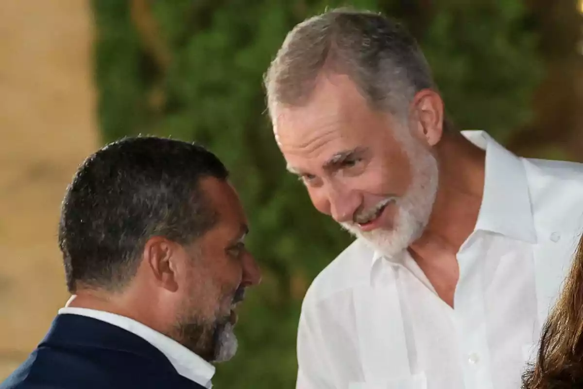 El rey Felipe y Jaime Anglada conversan sonrientes en un ambiente al aire libre.