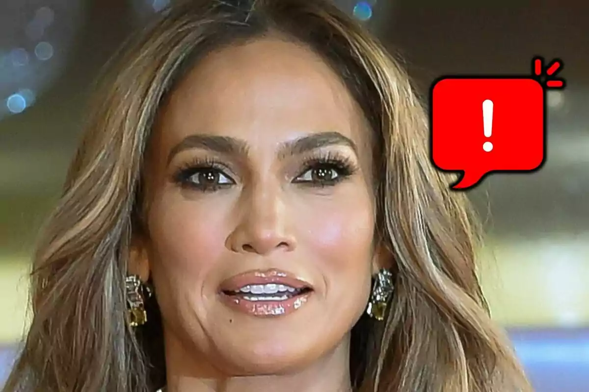 Close-up of Jennifer Lopez with a serious expression and a red speech bubble with a white exclamation mark next to her.