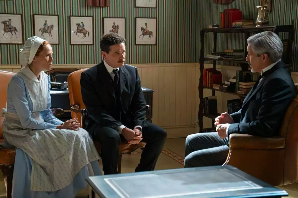 Pía, Ricardo i Cristóbal vestides amb roba d’època conversen assegudes en una oficina elegant decorada amb quadres de cavalls i prestatgeries plenes de llibres. Captura de 'La Promesa' Pía, Ricardo i Cristóbal vestides amb roba d’època conversen assegudes en una oficina elegant decorada amb quadres de cavalls i prestatgeries plenes de llibres. Captura de 'La Promesa'