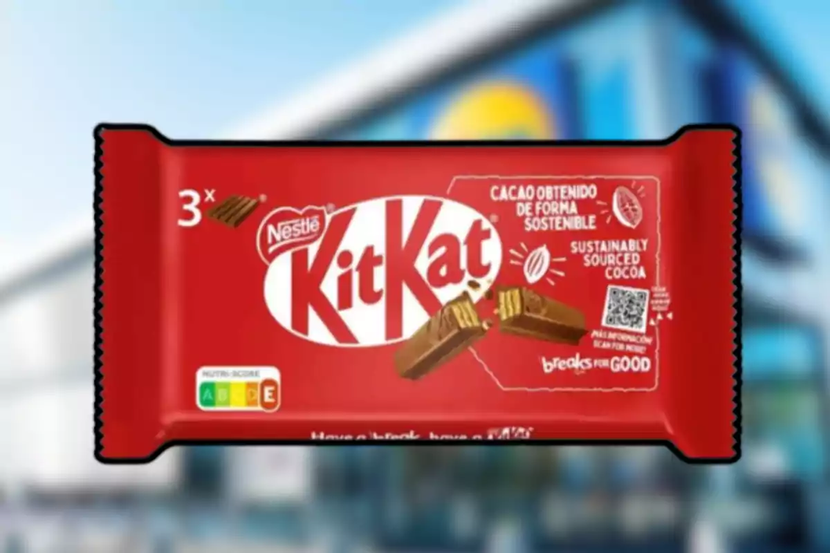 Embalatge de xocolata Kit Kat de Nestlé de color vermell amb informació sobre cacau sostenible i un fons desenfocat d’una botiga Embalatge de xocolata Kit Kat de Nestlé de color vermell amb informació sobre cacau sostenible i un fons desenfocat d’una botiga