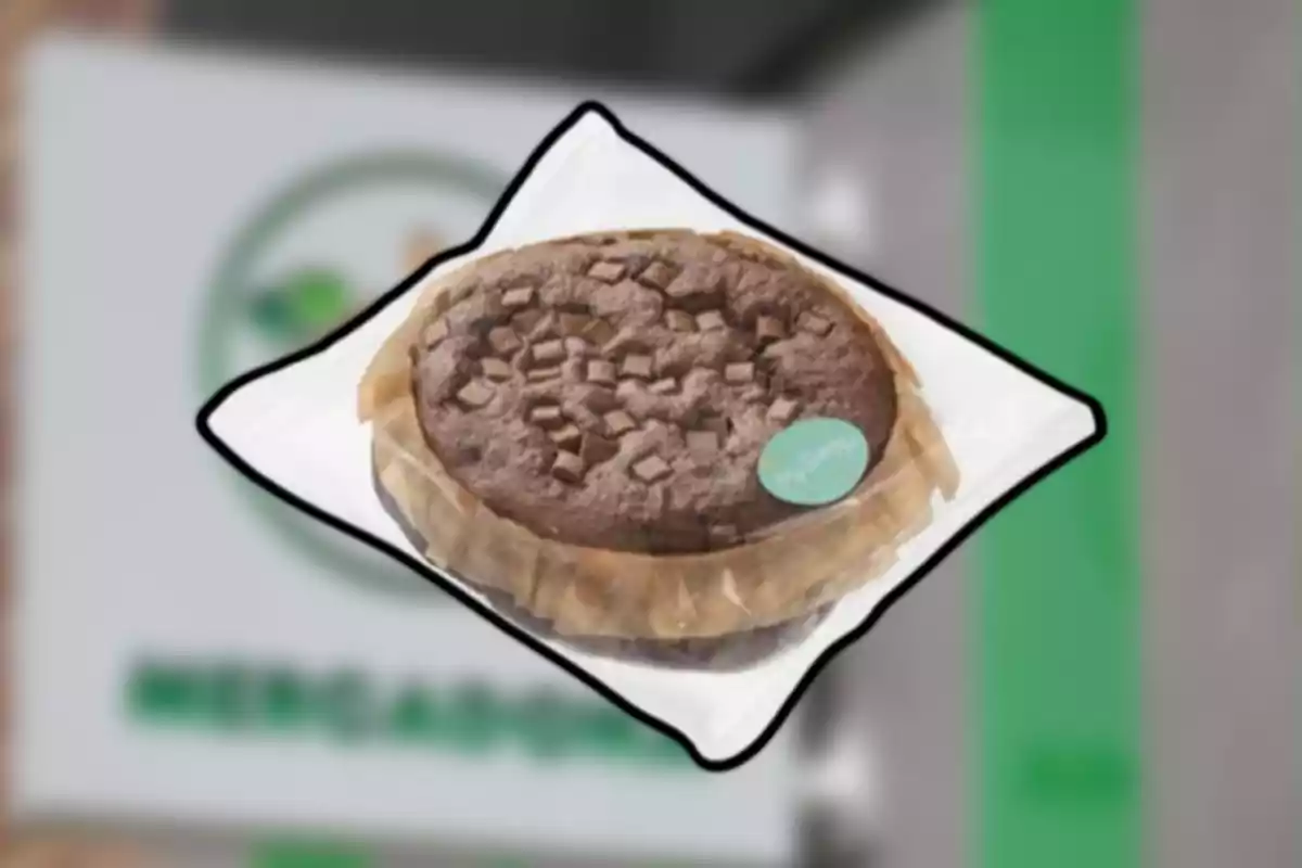 Pastís de xocolata amb trossos al damunt embolicat amb paper sobre un fons desenfocat de supermercat Pastís de xocolata amb trossos al damunt embolicat amb paper sobre un fons desenfocat de supermercat