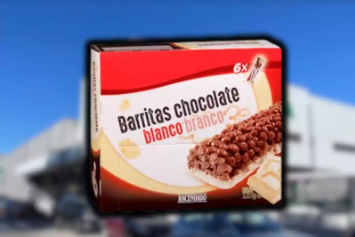 Caixa de barretes de xocolata blanca de la marca Hacendado sobre un fons desenfocat de supermercat i cel blau