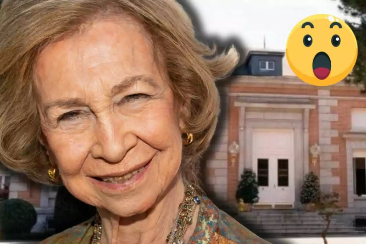 La reina Sofia somrient en primer pla amb un edifici de fons i un emoji de sorpresa a la cantonada superior dreta