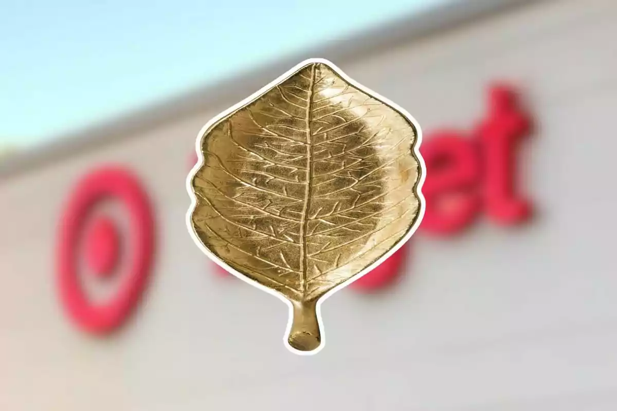 Decorative golden leaf against a blurred background of a store with a red logo Decorative golden leaf against a blurred background of a store with a red logo
