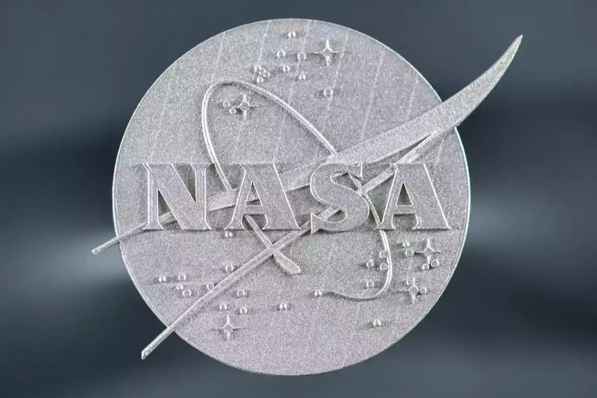 Logotip platejat de la NASA en relleu sobre un fons gris fosc Logotip platejat de la NASA en relleu sobre un fons gris fosc