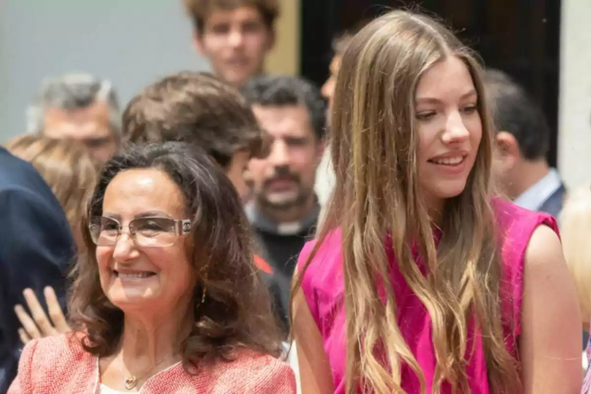 Paloma Rocasolano and Infanta Sofía smile while surrounded by other people at an outdoor event. Paloma Rocasolano and Infanta Sofía smile while surrounded by other people at an outdoor event.