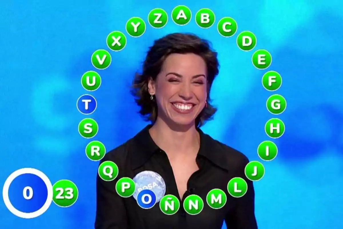 Rosa Rodríguez somrient participant en un concurs de televisió amb lletres de l’abecedari en cercles verds formant un semicercle al seu voltant i un marcador amb el número 23. Captura de ‘Pasapalabra’ Rosa Rodríguez somrient participant en un concurs de televisió amb lletres de l’abecedari en cercles verds formant un semicercle al seu voltant i un marcador amb el número 23. Captura de ‘Pasapalabra’