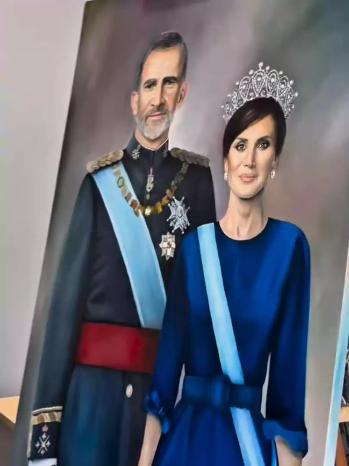 Pintura de Felipe VI y la reina Letizia con vestimenta formal y bandas azules sobre un fondo neutro