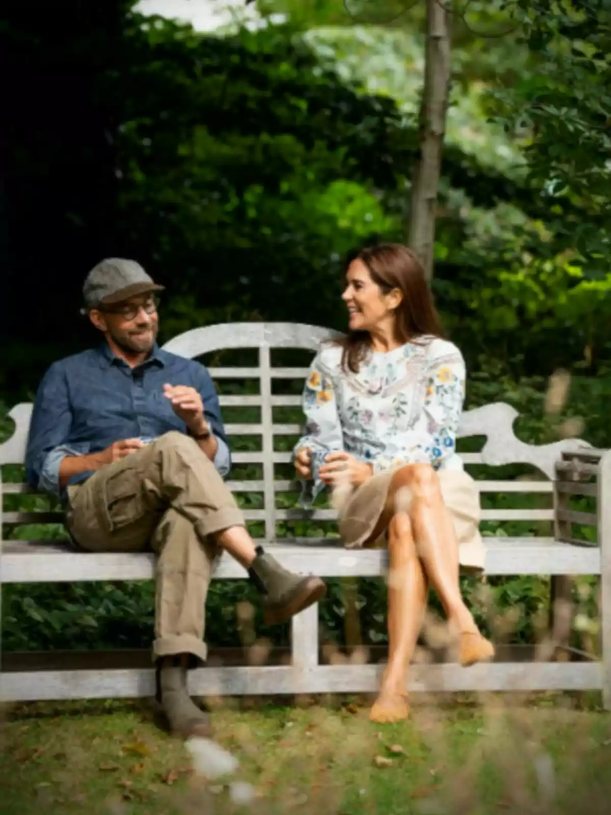 Mary de Dinamarca i un periodista asseguts en un banc de fusta conversen i somriuen en un jardí envoltat de vegetació Mary de Dinamarca i un periodista asseguts en un banc de fusta conversen i somriuen en un jardí envoltat de vegetació