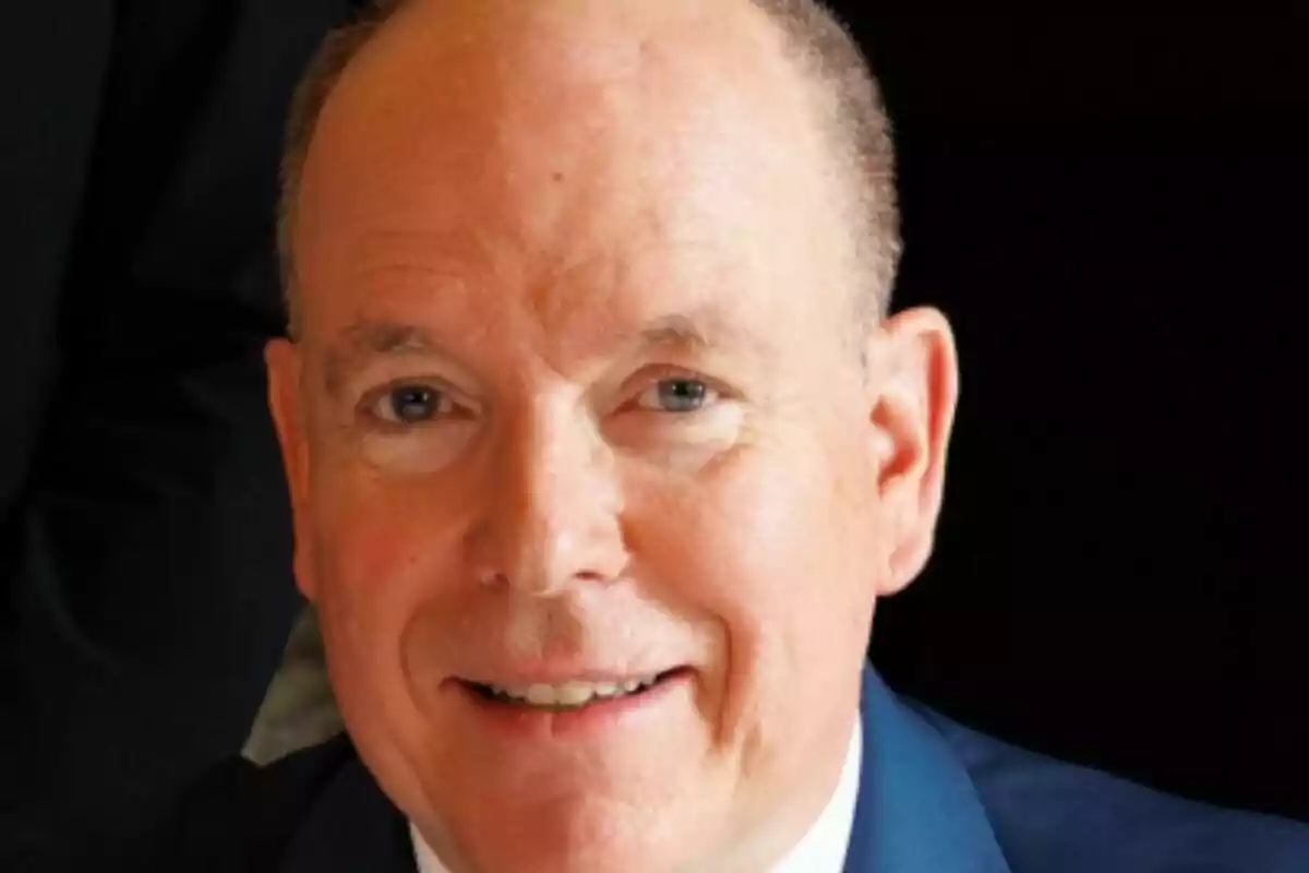 Primer plano de Alberto de Mónaco con traje azul sonriendo frente a la cámara.