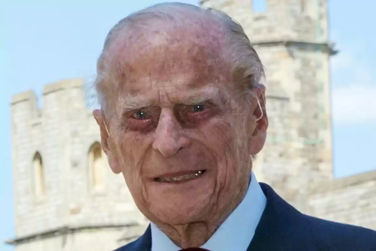 Felip d’Edimburg amb vestit fosc somriu davant d’una construcció de pedra antiga Felip d’Edimburg amb vestit fosc somriu davant d’una construcció de pedra antiga