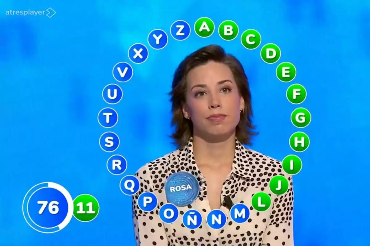 Una concursant en un programa de televisió, que és Rosa Rodríguez a 'Pasapalabra', amb lletres de l'abecedari envoltant-la i un marcador de temps i encerts a la pantalla. Una concursant en un programa de televisió, que és Rosa Rodríguez a 'Pasapalabra', amb lletres de l'abecedari envoltant-la i un marcador de temps i encerts a la pantalla.