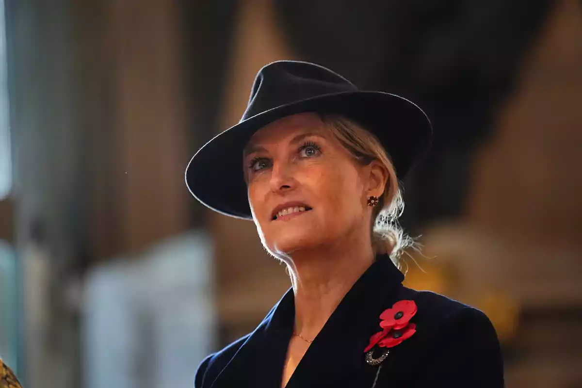 Sophie, duquesa de Edimburgo, con sombrero negro y abrigo oscuro decorado con flores rojas mirando hacia arriba con expresión serena Sophie, duquesa de Edimburgo, con sombrero negro y abrigo oscuro decorado con flores rojas mirando hacia arriba con expresión serena