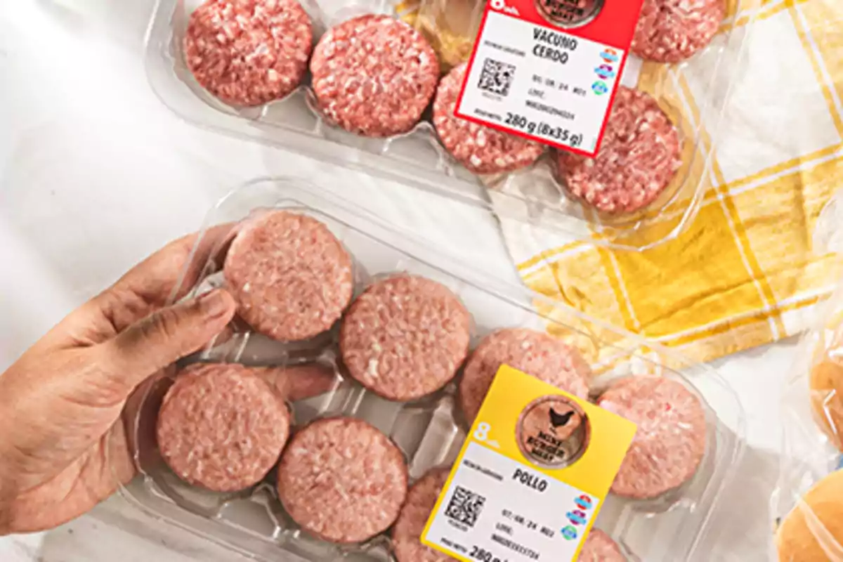 Safates de mini hamburgueses de pollastre i de vedella amb porc en envasos de plàstic sobre una taula amb estovalla groga Safates de mini hamburgueses de pollastre i de vedella amb porc en envasos de plàstic sobre una taula amb estovalla groga