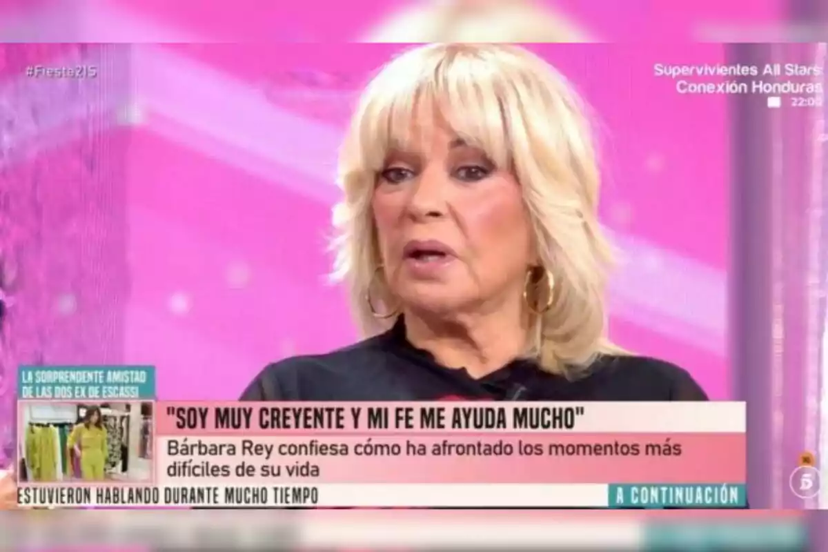 Bárbara Rey con cabello corto y flequillo, usando aretes dorados y blusa negra, aparece en un programa de televisión con fondo rosa y subtítulos que mencionan su fe y cómo ha afrontado momentos difíciles. Bárbara Rey con cabello corto y flequillo, usando aretes dorados y blusa negra, aparece en un programa de televisión con fondo rosa y subtítulos que mencionan su fe y cómo ha afrontado momentos difíciles.