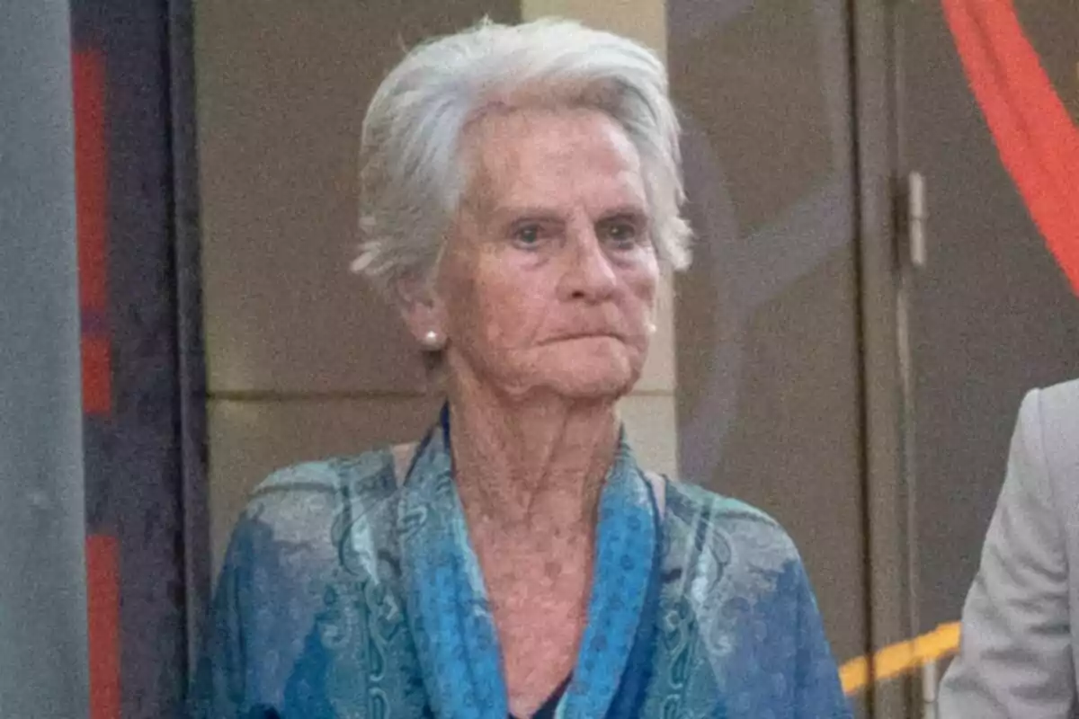 Claire Liebaert vestida amb una brusa blava estampada, mirant al front amb expressió seriosa. Claire Liebaert vestida amb una brusa blava estampada, mirant al front amb expressió seriosa.