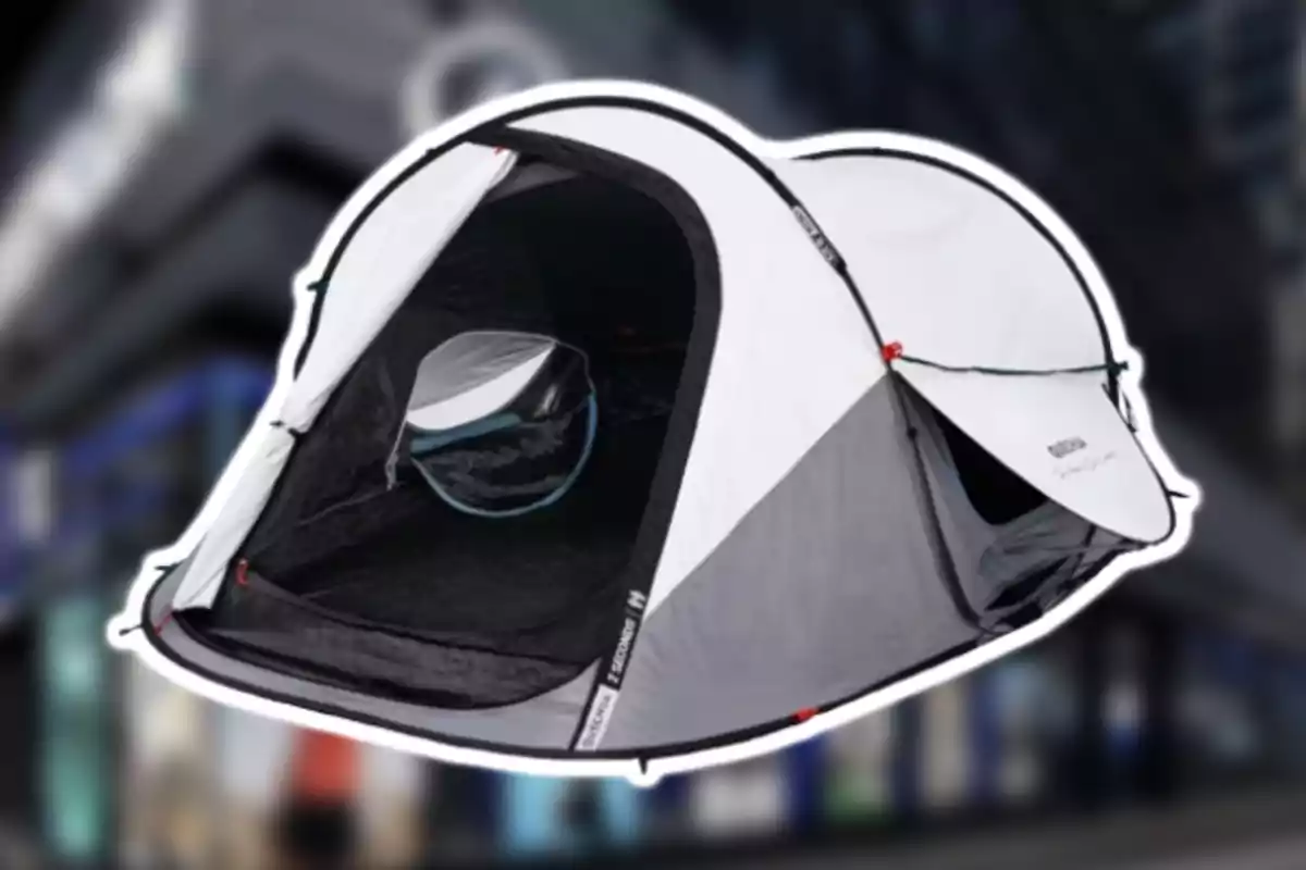 Tenda de campanya grisa i blanca amb la porta oberta sobre un fons urbà desenfocat Tenda de campanya grisa i blanca amb la porta oberta sobre un fons urbà desenfocat