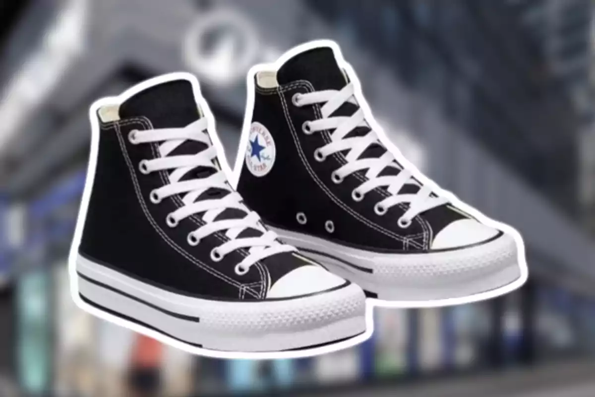 Un parell de vambes negres tipus bota amb cordons blancs i sola blanca sobre un fons desenfocat