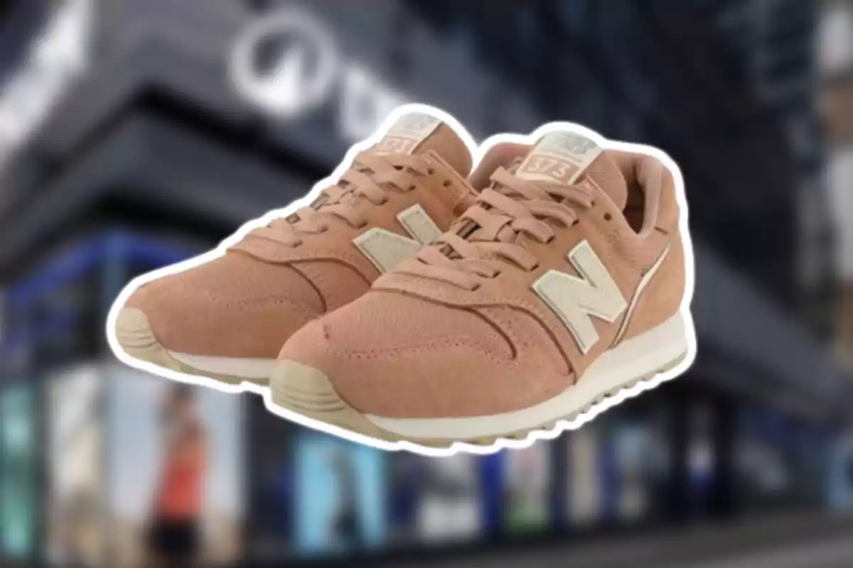 Sabatilles esportives de color beix de la marca New Balance model 373 sobre un fons desenfocat de botiga Sabatilles esportives de color beix de la marca New Balance model 373 sobre un fons desenfocat de botiga