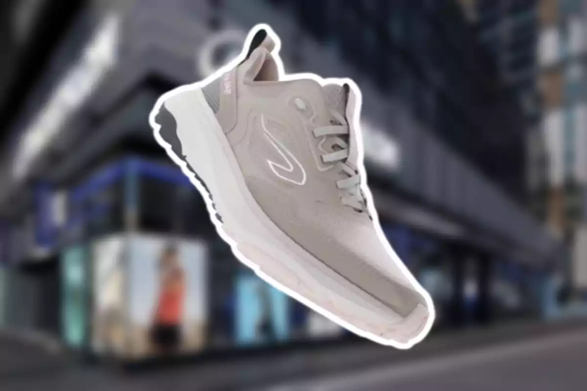 Sabata esportiva gris clar amb detalls blancs i fons urbà desenfocat