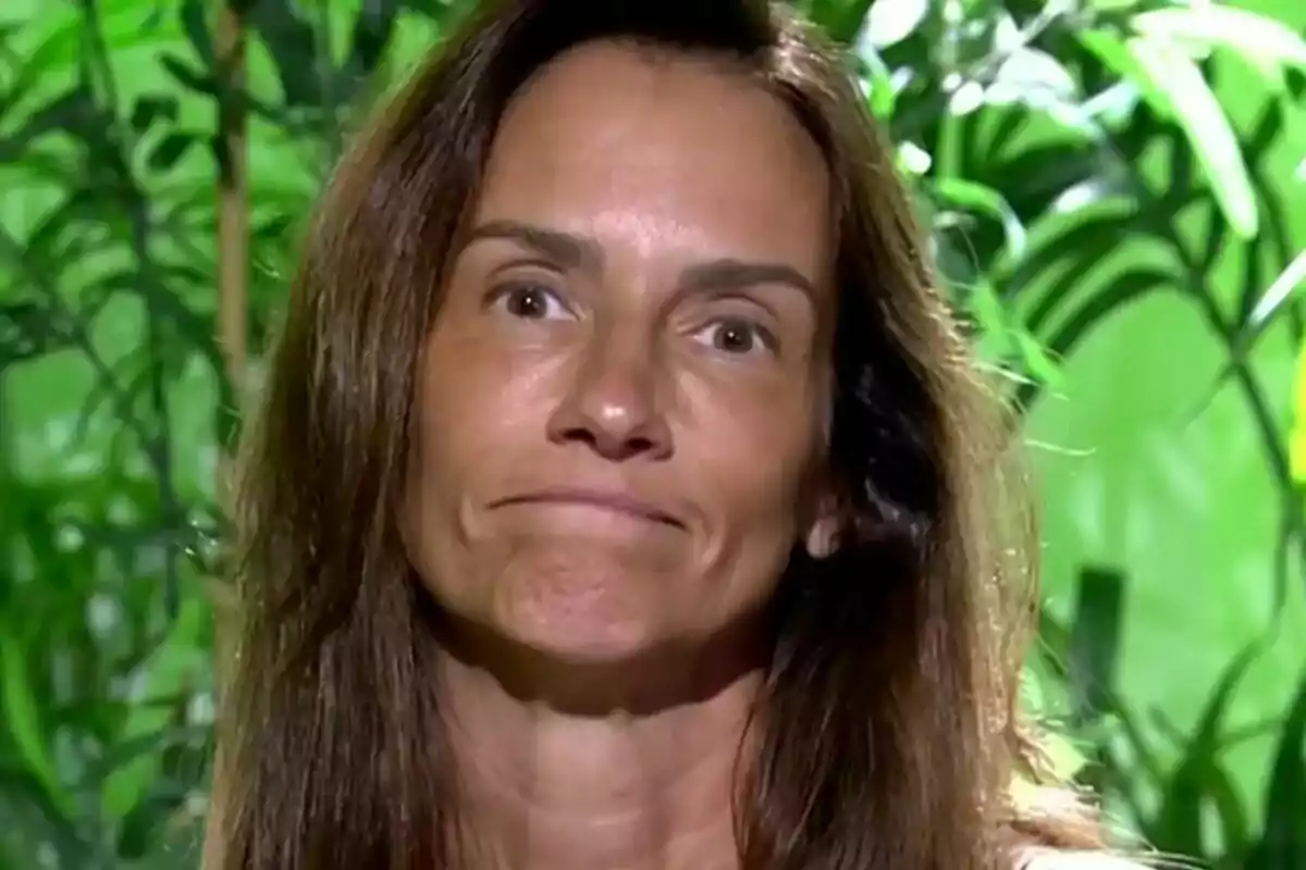 Primer pla d’Elena Rodríguez amb expressió seriosa davant d’un fons de plantes verdes.