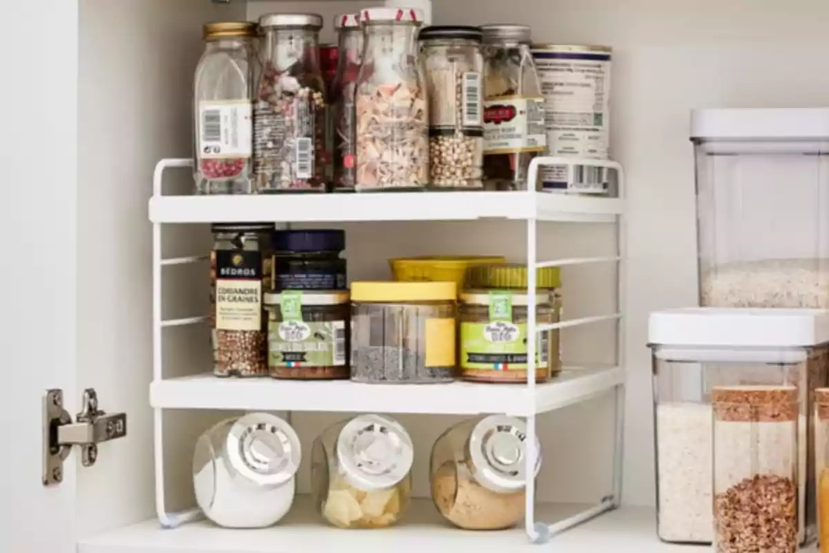 Estant organitzador de cuina amb pots d'espècies i recipients d'aliments emmagatzemats ordenadament dins d'un armari blanc Estant organitzador de cuina amb pots d'espècies i recipients d'aliments emmagatzemats ordenadament dins d'un armari blanc