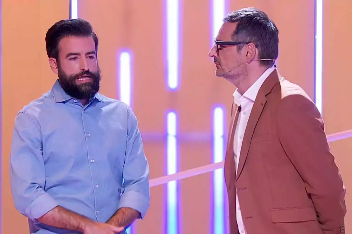 Rafa Castaño i Eugeni Alemany conversen en un plató d’Agafa’t a la butaca amb llums de neó i fons taronja Rafa Castaño i Eugeni Alemany conversen en un plató d’Agafa’t a la butaca amb llums de neó i fons taronja