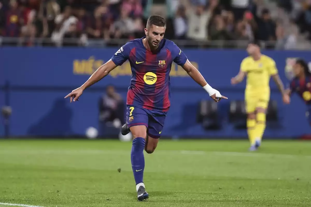 Futbolista del Barcelona celebrando un gol en el campo con los brazos extendidos y aficionados de fondo Futbolista del Barcelona celebrando un gol en el campo con los brazos extendidos y aficionados de fondo