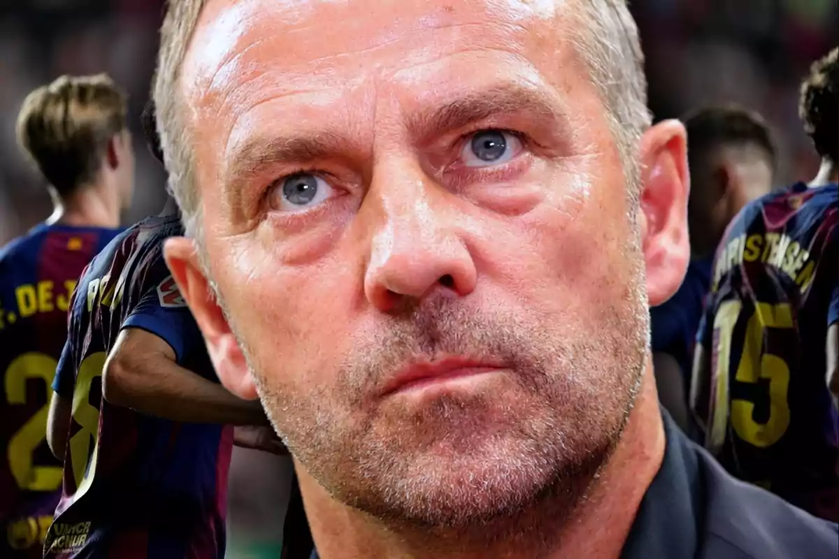 Primer plano de un hombre de expresión seria con jugadores de fútbol del Barcelona desenfocados al fondo Primer plano de un hombre de expresión seria con jugadores de fútbol del Barcelona desenfocados al fondo