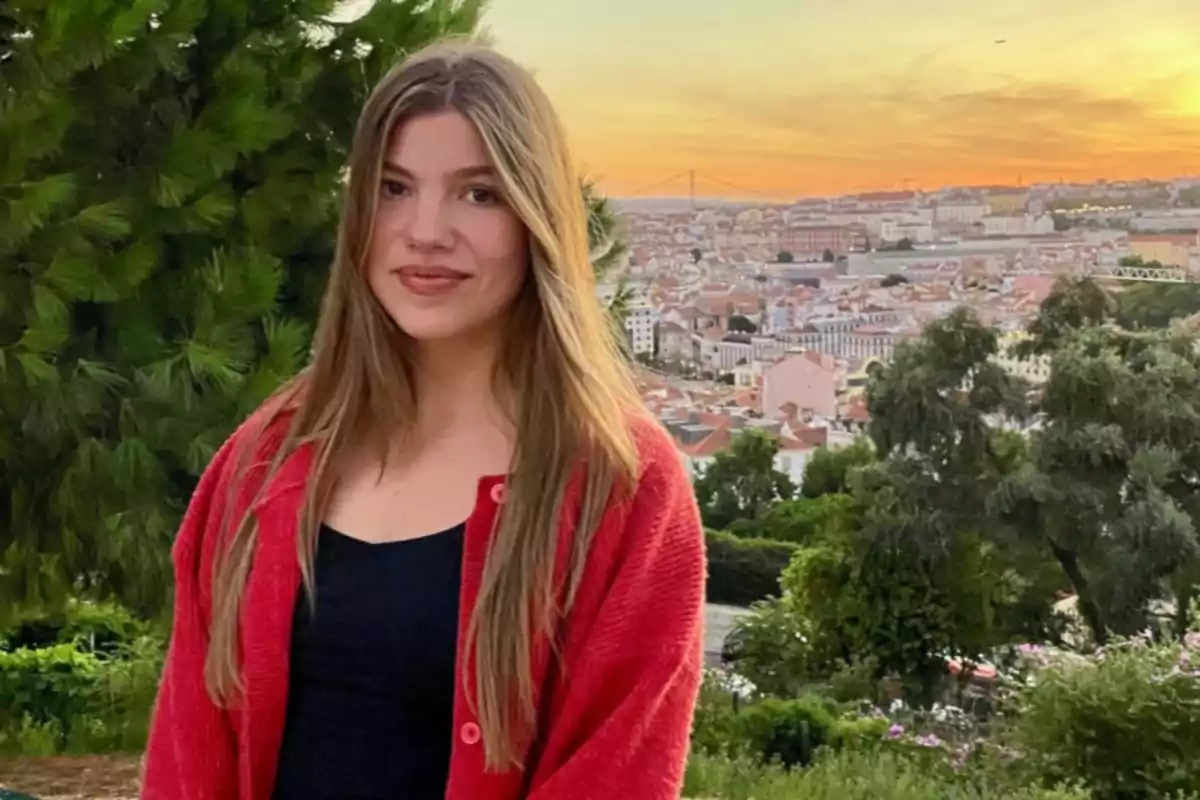 La infanta Sofia amb cabell llarg i solt, portant un jersei vermell i samarreta negra, posant en un mirador amb vista a una ciutat al capvespre La infanta Sofia amb cabell llarg i solt, portant un jersei vermell i samarreta negra, posant en un mirador amb vista a una ciutat al capvespre