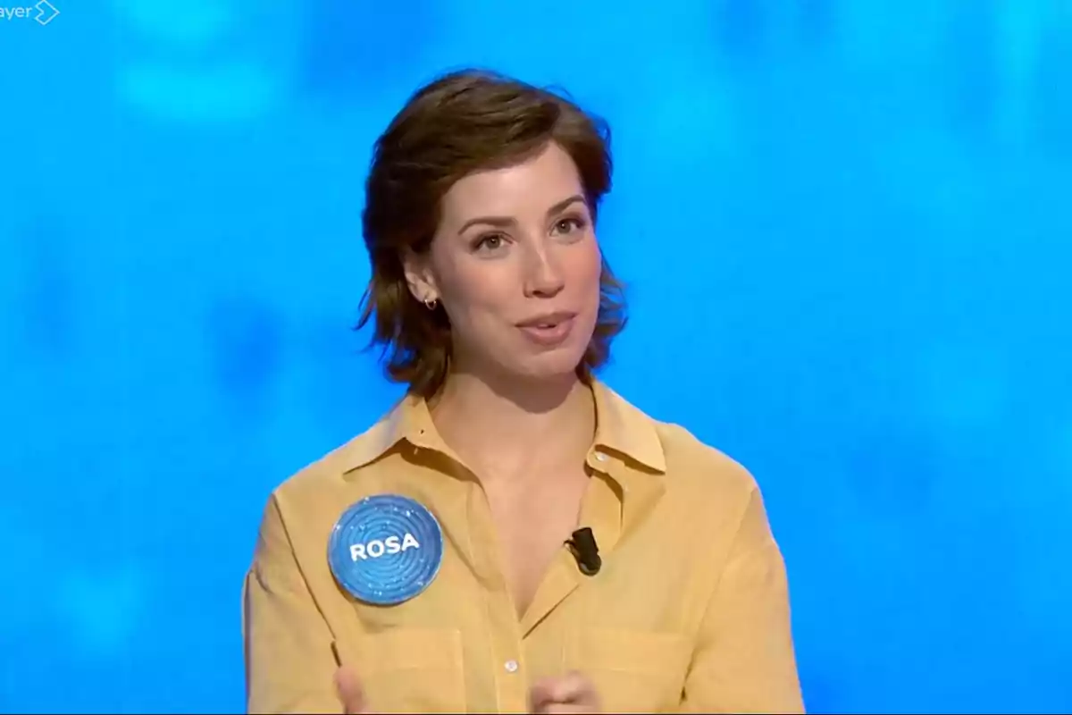 Rosa amb una camisa groga i un identificador blau que diu el seu nom sobre un fons blau