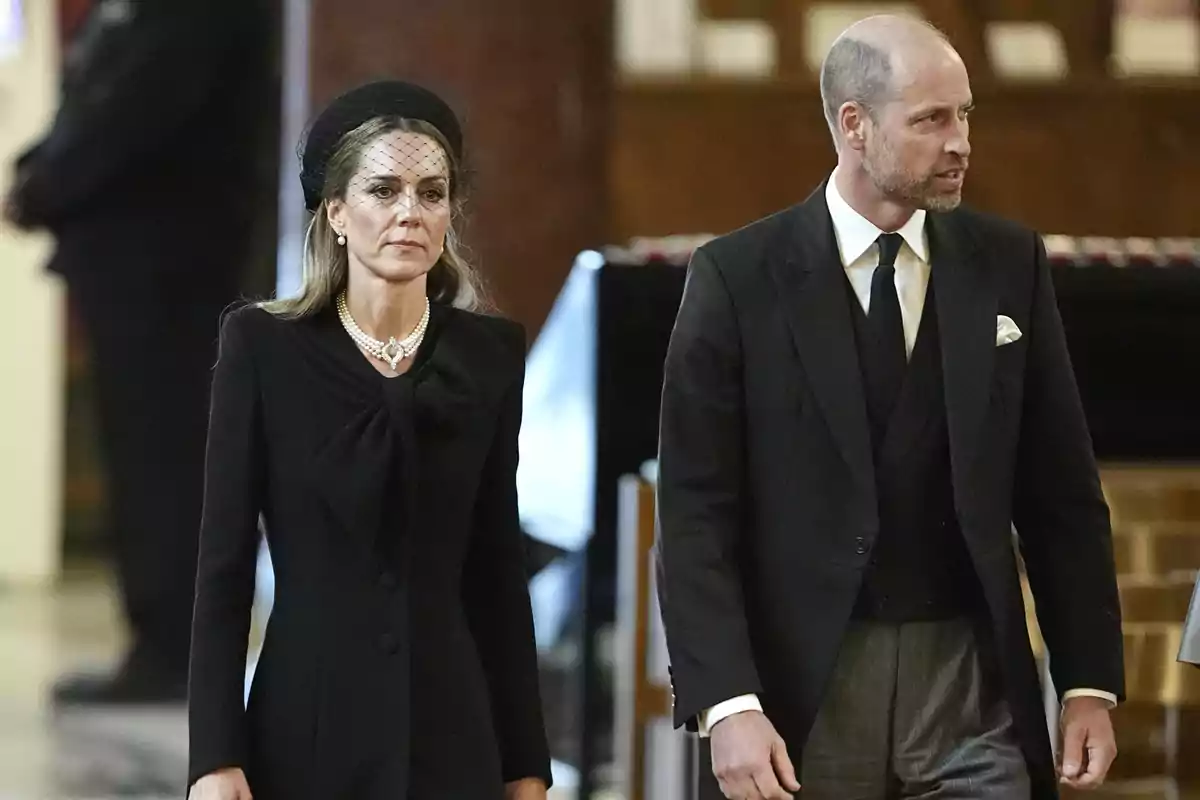 Kate Middleton i el príncep Guillem vestits de negre caminen junts en un ambient formal Kate Middleton i el príncep Guillem vestits de negre caminen junts en un ambient formal
