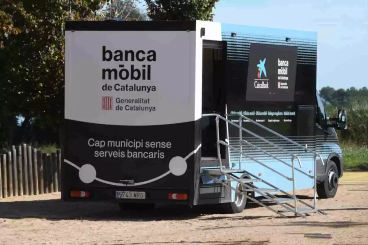Furgoneta de banca mòbil de Catalunya amb rampa d'accés estacionada en una zona a l'aire lliure Furgoneta de banca mòbil de Catalunya amb rampa d'accés estacionada en una zona a l'aire lliure