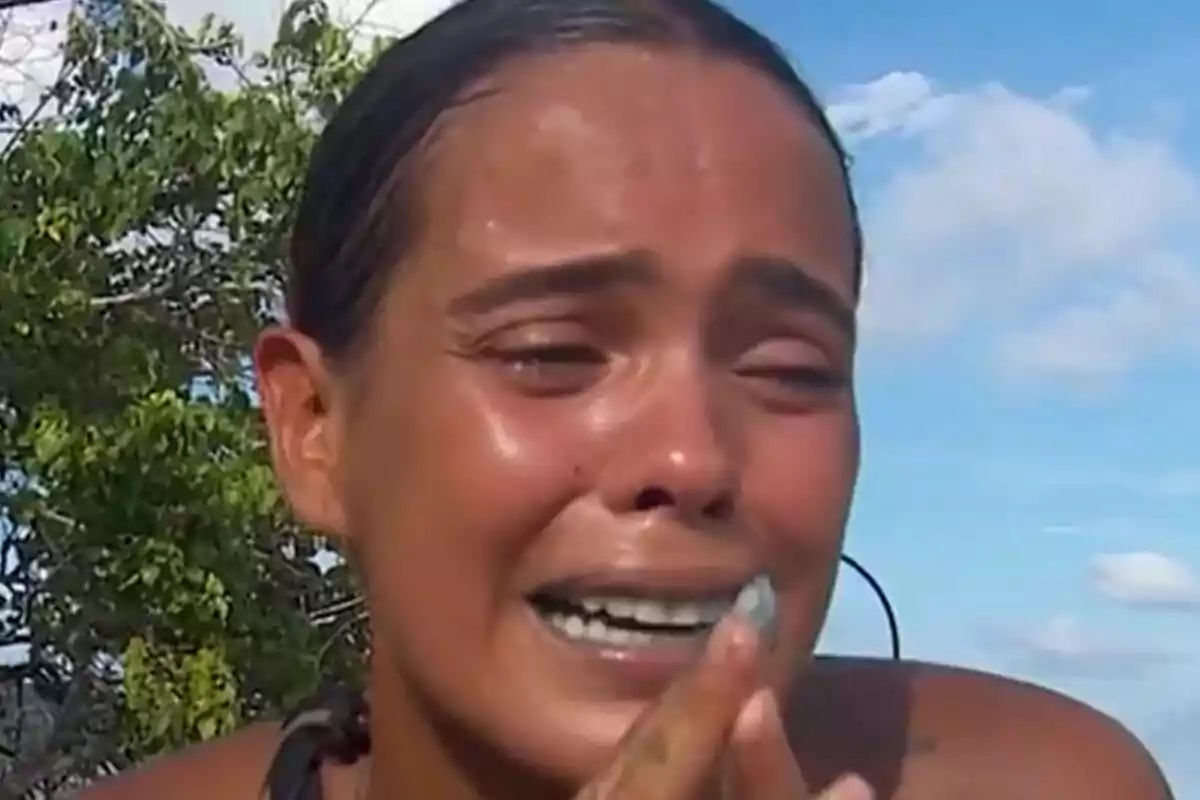 Dona jove plorant a l’aire lliure amb expressió d’angoixa i les mans juntes davant del seu rostre