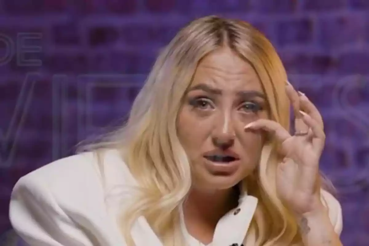 Dona rossa amb expressió de tristesa i llàgrimes als ulls, vestida amb jaqueta blanca i fons morat desenfocat Dona rossa amb expressió de tristesa i llàgrimes als ulls, vestida amb jaqueta blanca i fons morat desenfocat