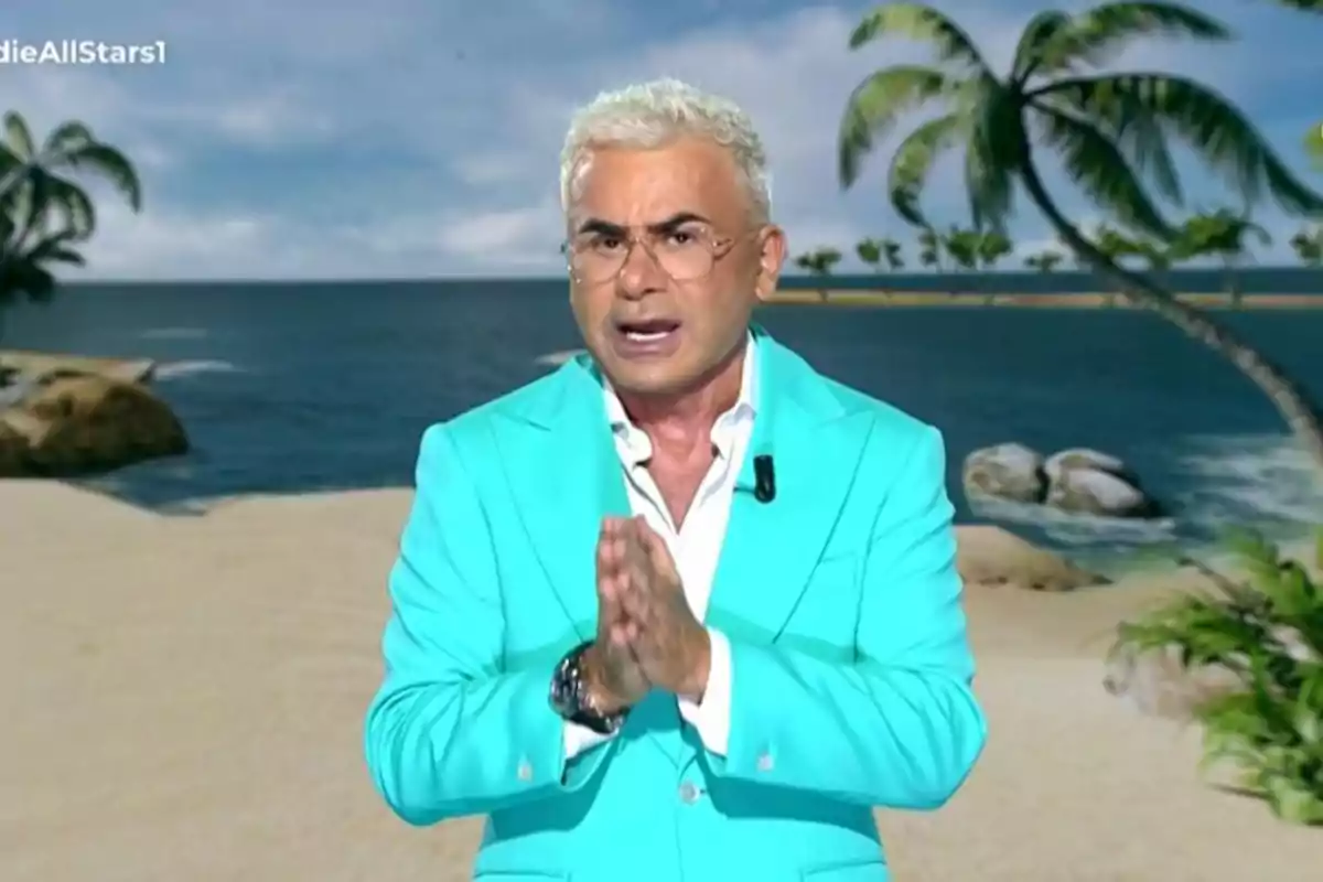 Home de cabells canosos i ulleres amb jaqueta turquesa parlant davant d’un fons de platja amb palmeres Home de cabells canosos i ulleres amb jaqueta turquesa parlant davant d’un fons de platja amb palmeres