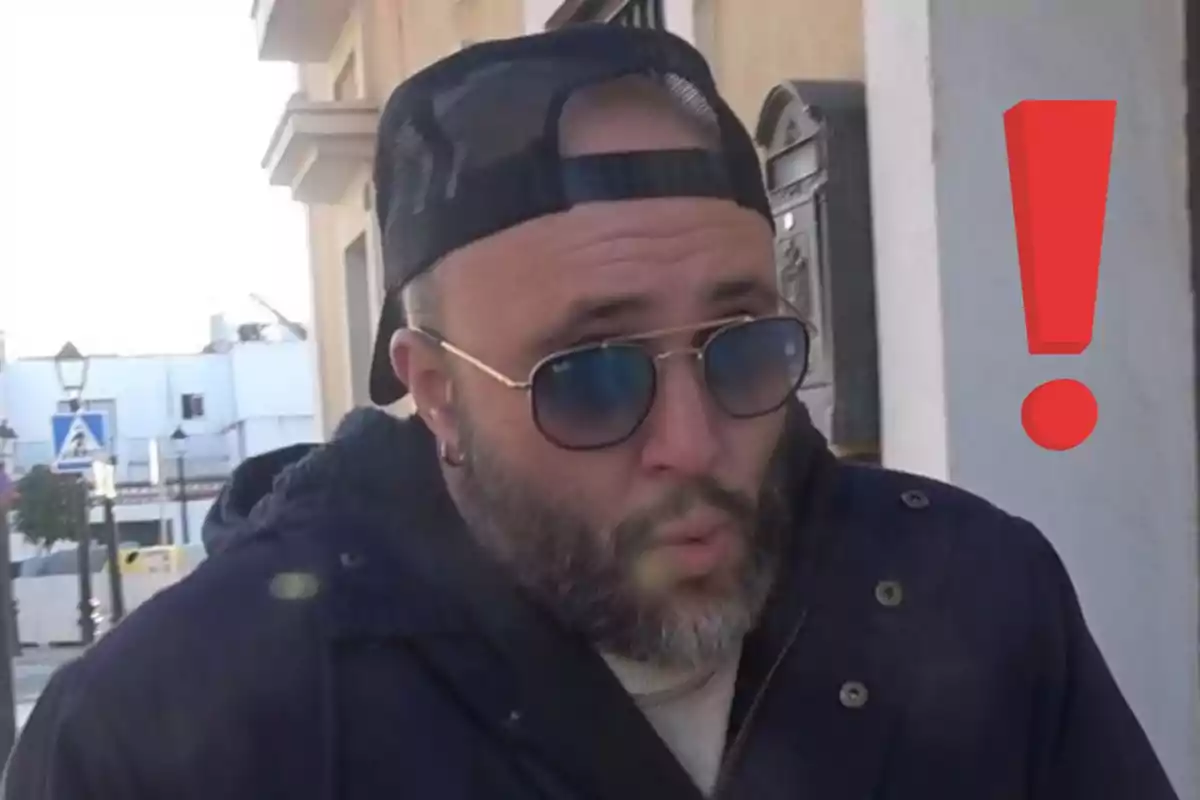 Kiko Rivera con barba y gafas de sol usando gorra hacia atrás, con un gesto de sorpresa y un signo de exclamación rojo al fondo Kiko Rivera con barba y gafas de sol usando gorra hacia atrás, con un gesto de sorpresa y un signo de exclamación rojo al fondo